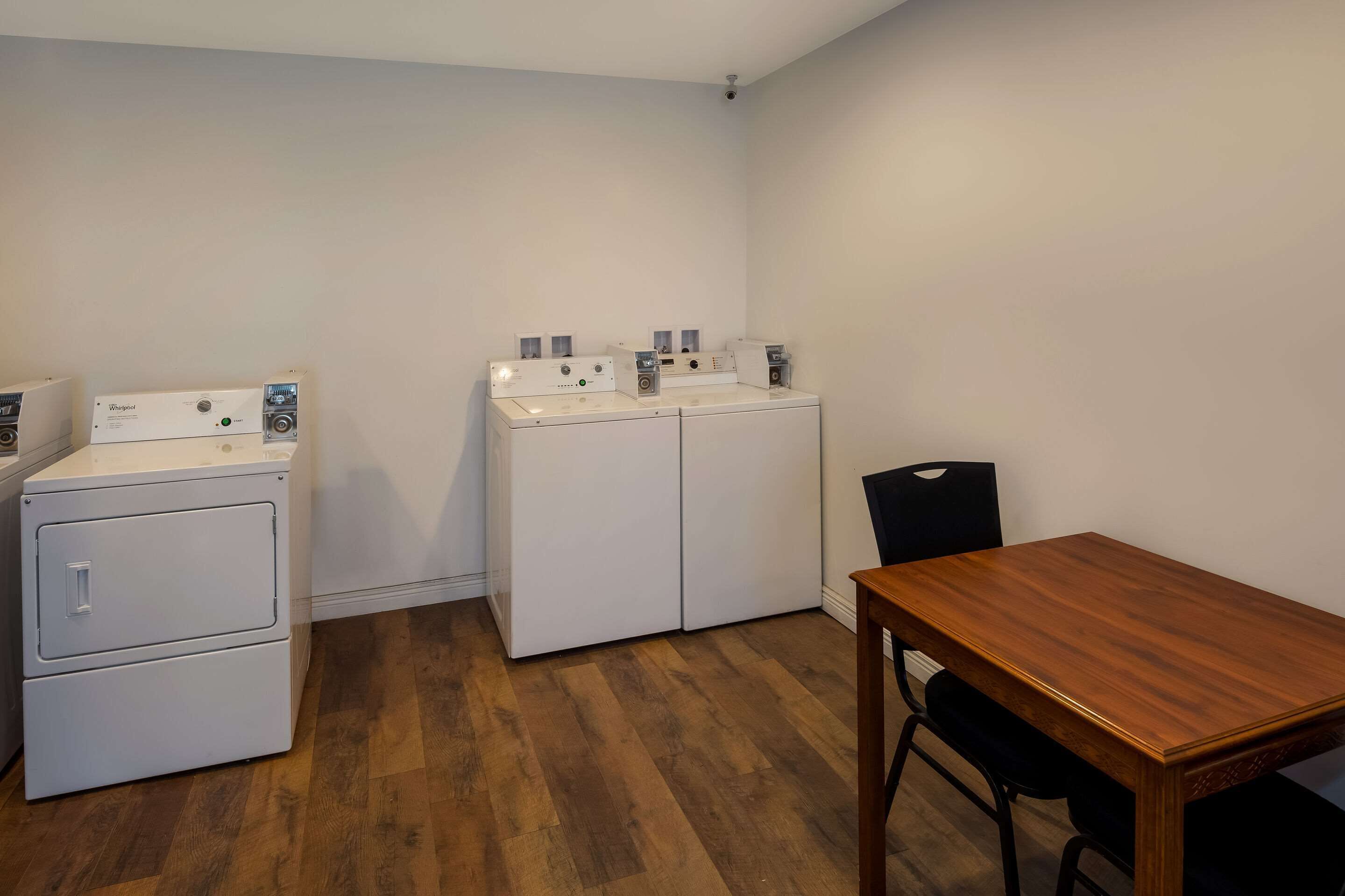 Una cocina compacta con una mesa y sillas de madera, una lavadora y una secadora.