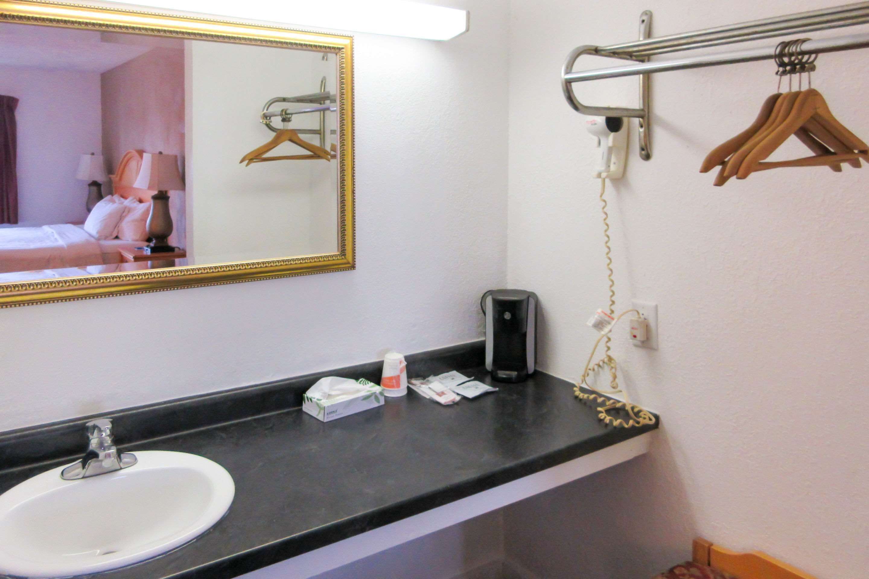 Ein Badezimmer im Hotel mit Waschbecken, Spiegel, Handtuchhalter und einem Föhn.