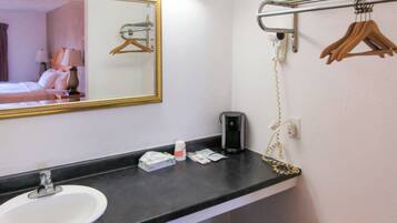Ein Badezimmer im Hotel mit Waschbecken, Spiegel, Handtuchhalter und einem Föhn.
