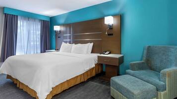 Una habitación de hotel con una cama grande, una mesita de noche, una silla y un escritorio.