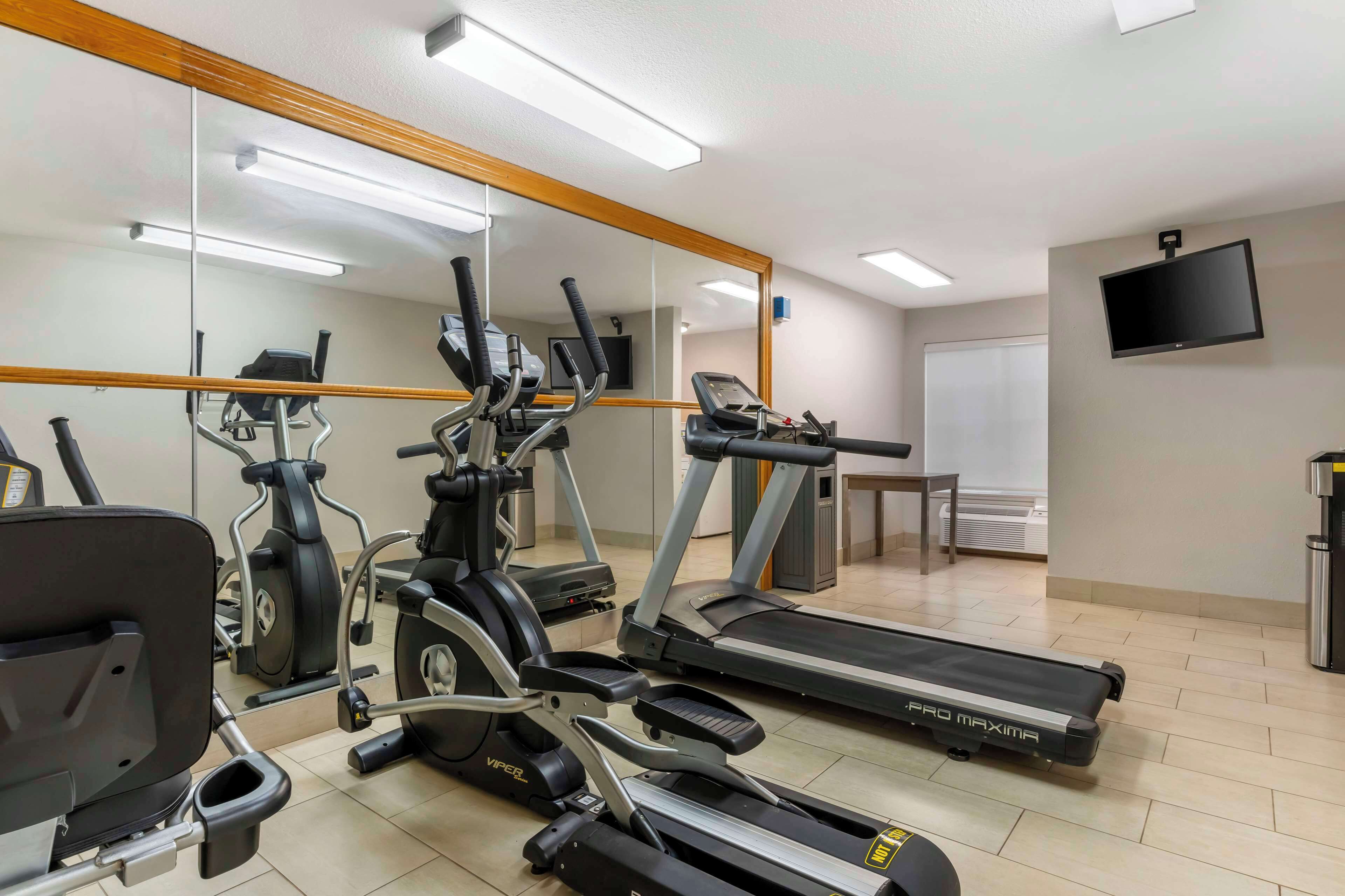 Un gimnasio con cintas de correr, elípticas y una bicicleta estática.