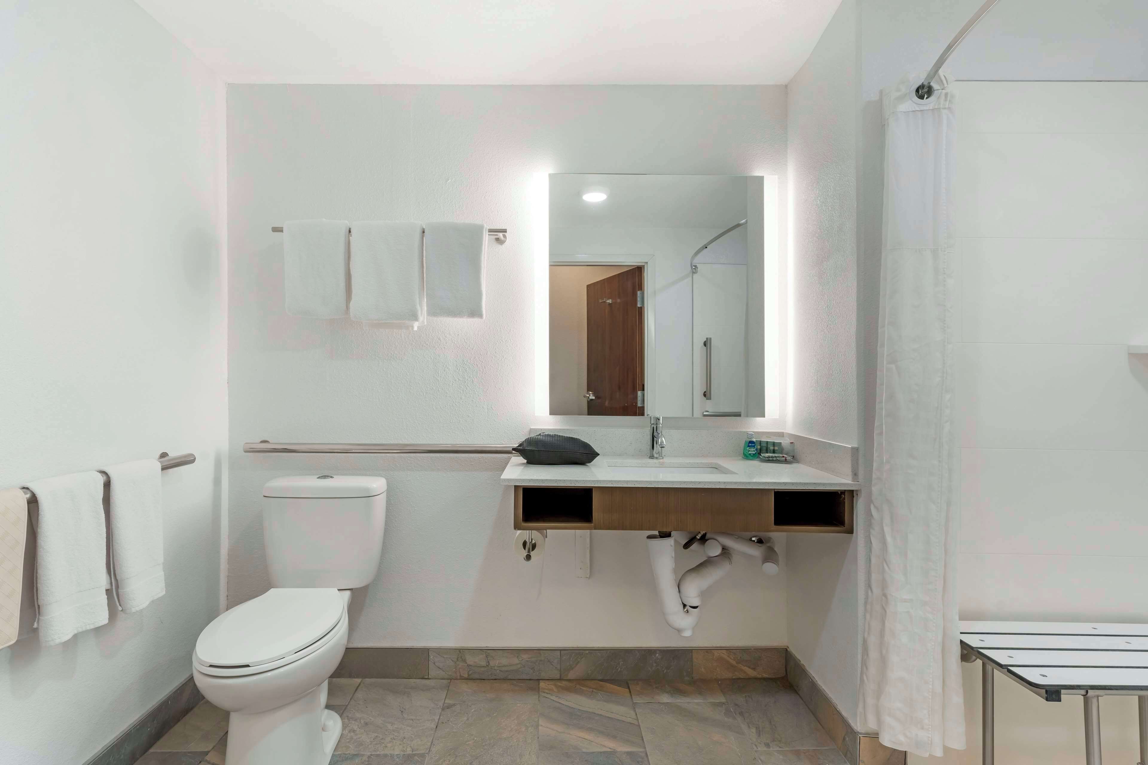 Een moderne badkamer met toilet, wastafel, spiegel en douchegordijn.
