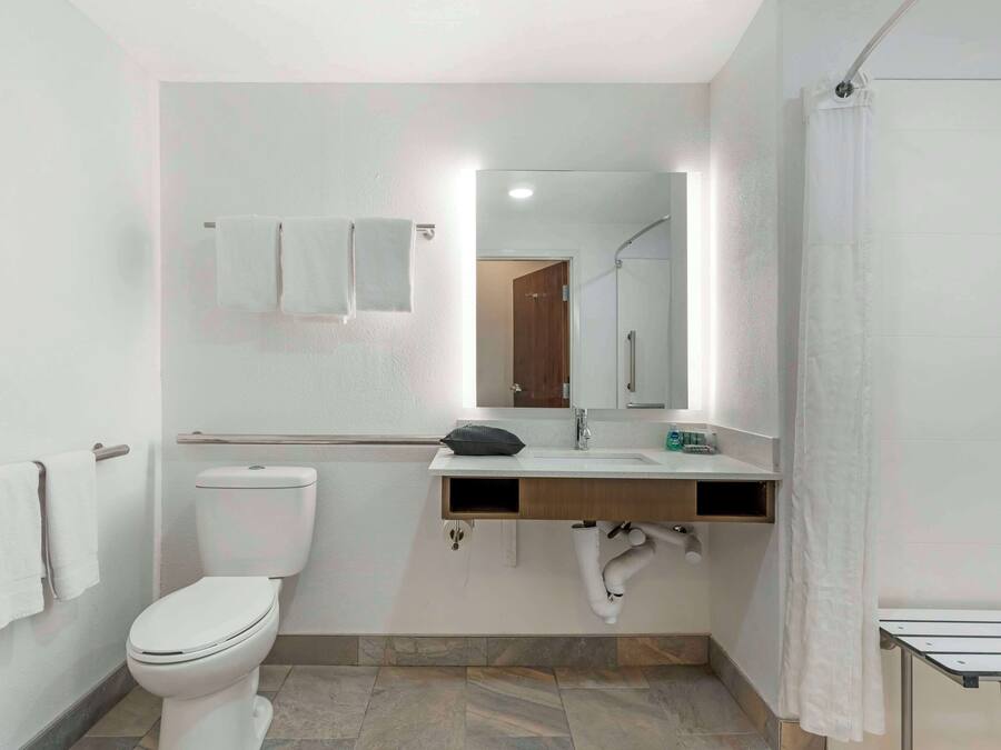 Een moderne badkamer met toilet, wastafel, spiegel en douchegordijn.