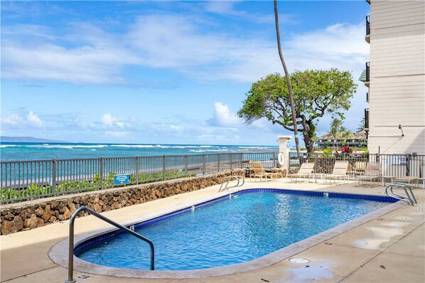 A swimming pool with a view of the ocean, a tree, and a building. - Kahana Reef - Maui Condo & Home (Lahaina)