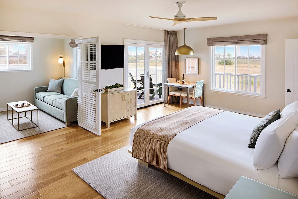 A bedroom with a bed, a desk, a sofa, and a TV.