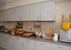 Una cocina con armarios, un frutero, una cafetera y un dispensador de jugo.