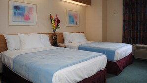 A hotel room with two beds, a vase with flowers, and two framed abstract paintings on the wall. - Rodeway Inn Willington North (Willington)