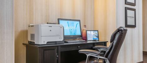 A modern office desk with a desktop computer, a printer, and a chair.