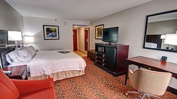 A hotel room with a bed, a desk, a chair, a TV, and a dresser.