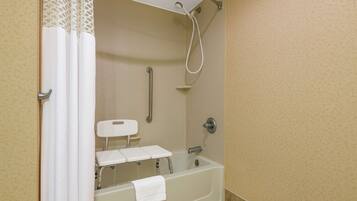 A bathroom with a bathtub, a shower, and a toilet with a grab bar.