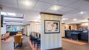 Eine Hotelhalle mit einer Rezeption, gerahmten Kunstwerken und einem Essbereich mit Stühlen und Tischen.