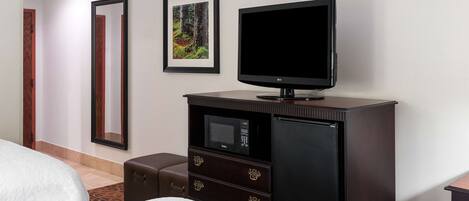 A hotel room with a bed, a TV on a cabinet, a microwave, and a refrigerator.