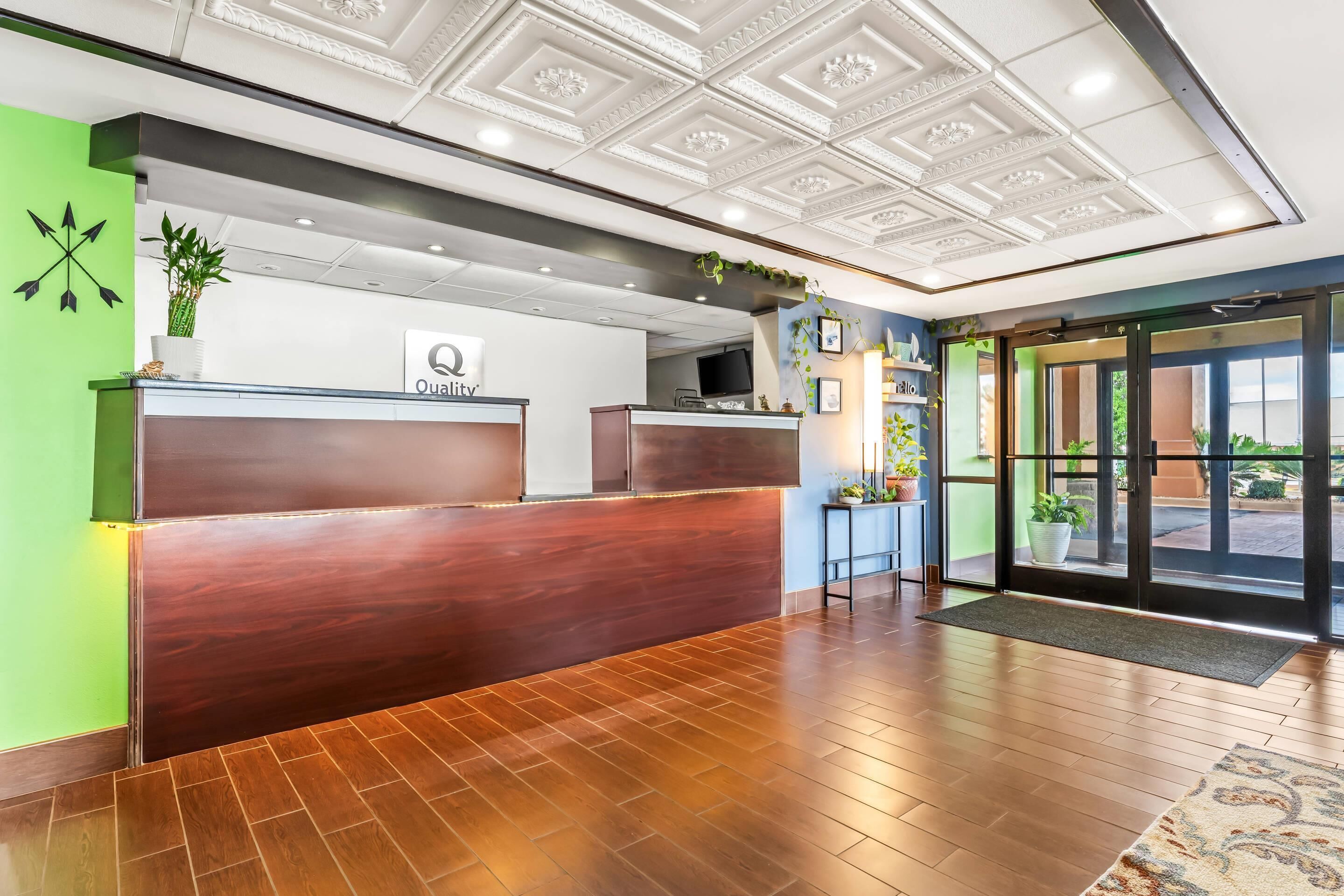 A hotel reception area with a wooden reception desk, a green wall, and a ceiling with decorative patterns.