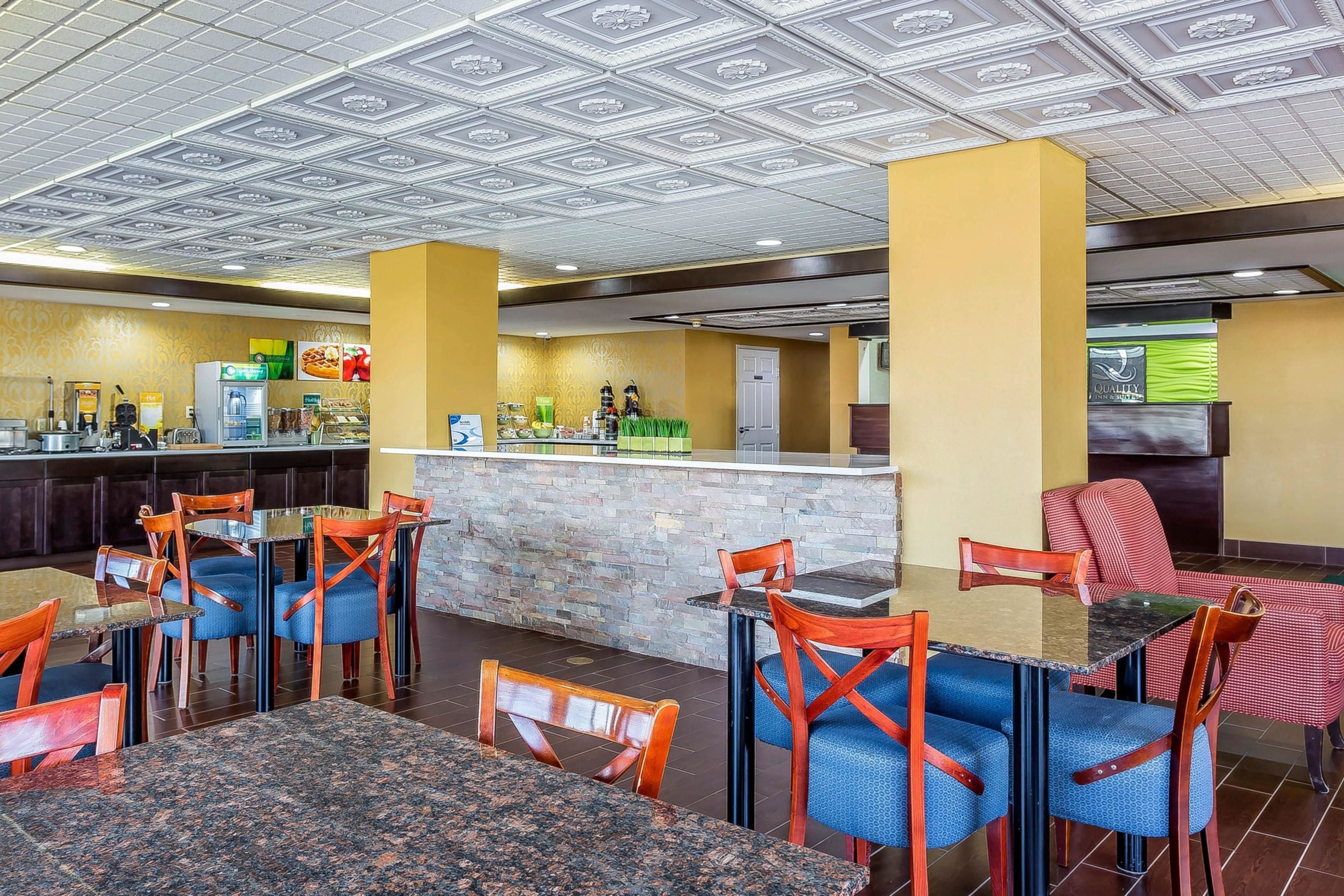 Ein Restaurant mit Granittischen und -stühlen, einem Barbereich und einer Küche im Hintergrund.