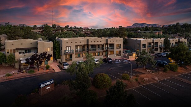 A multi-story motel with a parking lot, surrounded by trees and a mountainous backdrop. - Southwest Inn at Sedona (Sedona)