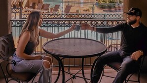 A couple sitting at a round metal table on a balcony with a view of a pool and mountains. - Southwest Inn at Sedona (Sedona)