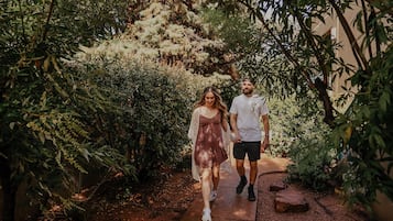 A couple walking on a pathway surrounded by dense foliage and trees.