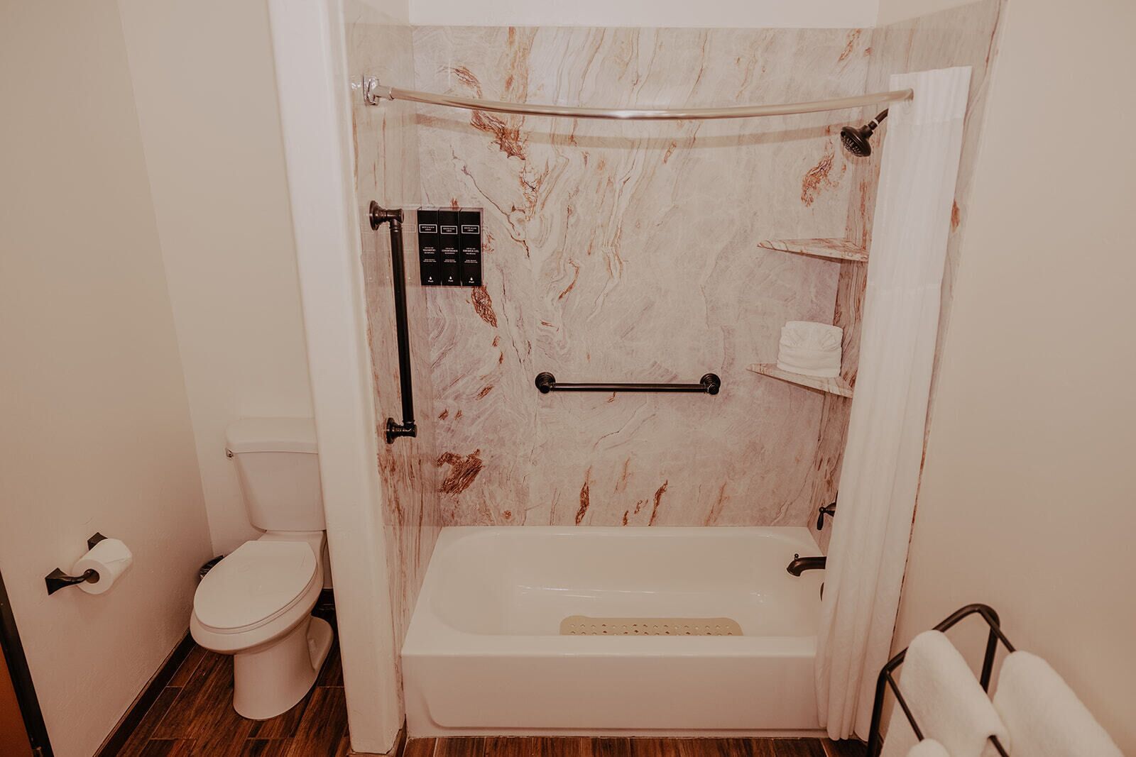 A bathroom with a toilet, a bathtub, and a shower area.