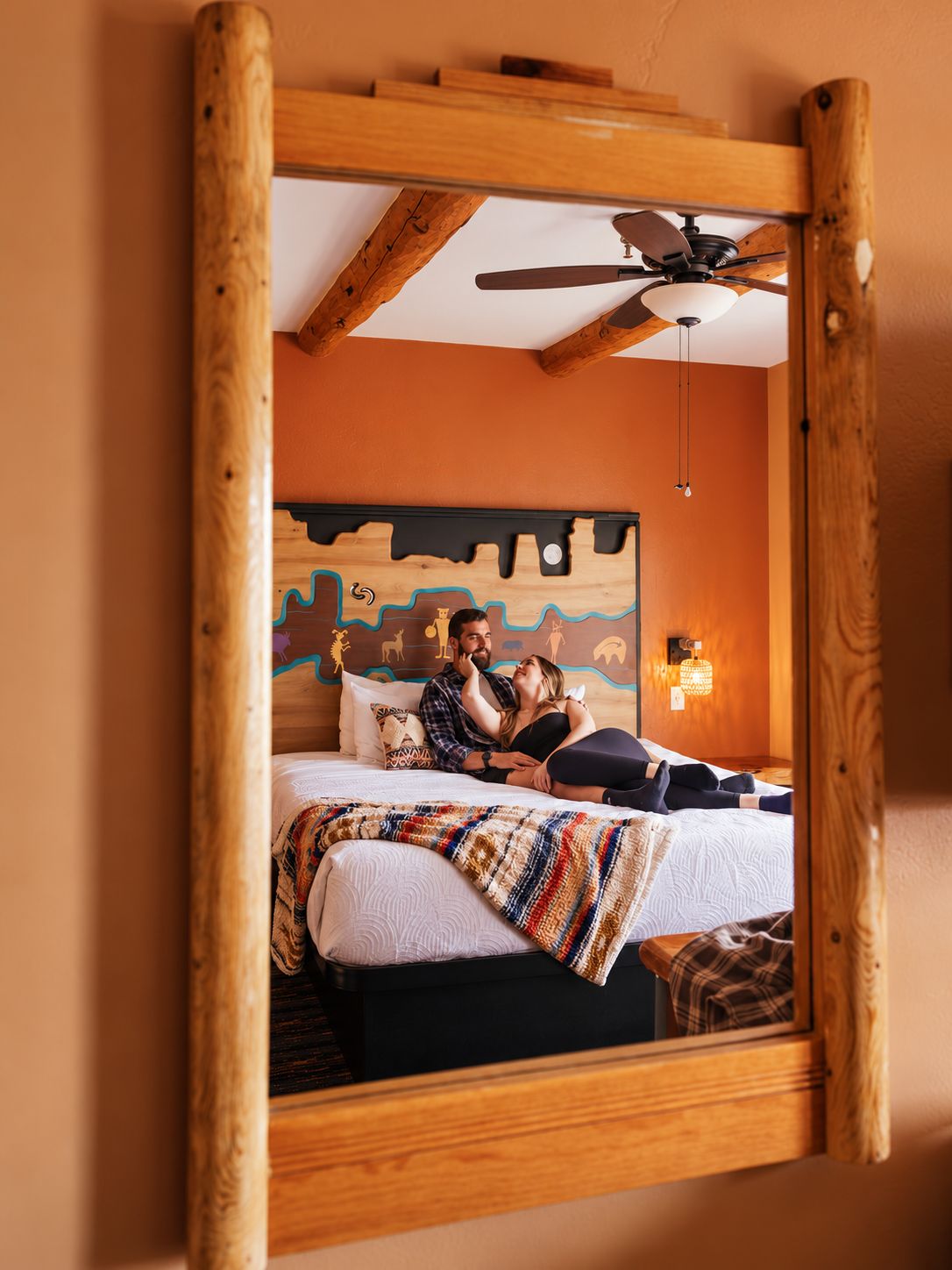 Ein Schlafzimmer mit einem Bett, einem Deckenventilator und einer Wand mit Wandgemälde.