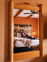 Ein Schlafzimmer mit einem Bett, einem Deckenventilator und einer Wand mit Wandgemälde.
