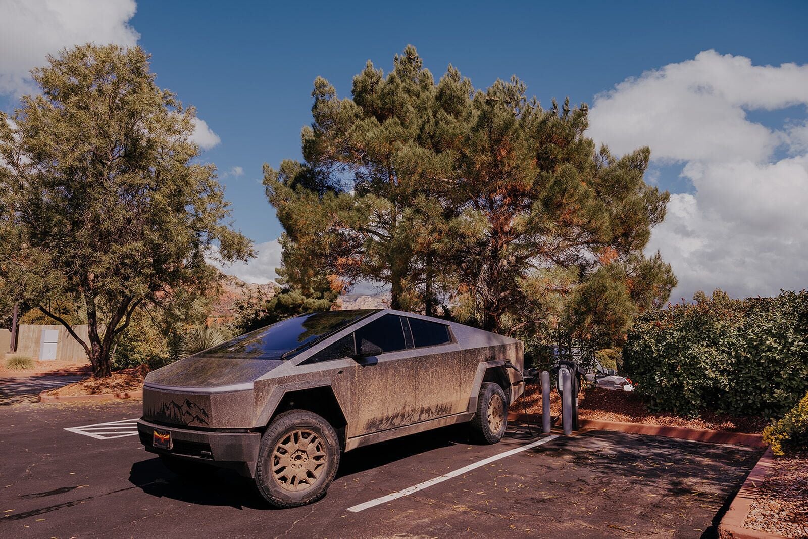 A futuristic vehicle parked in a parking lot with trees and a clear sky in the background.