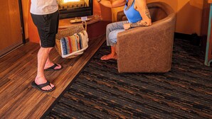 A man pouring a drink into a glass for a seated woman in a room with orange walls and a wooden ceiling. - Southwest Inn at Sedona (Sedona)