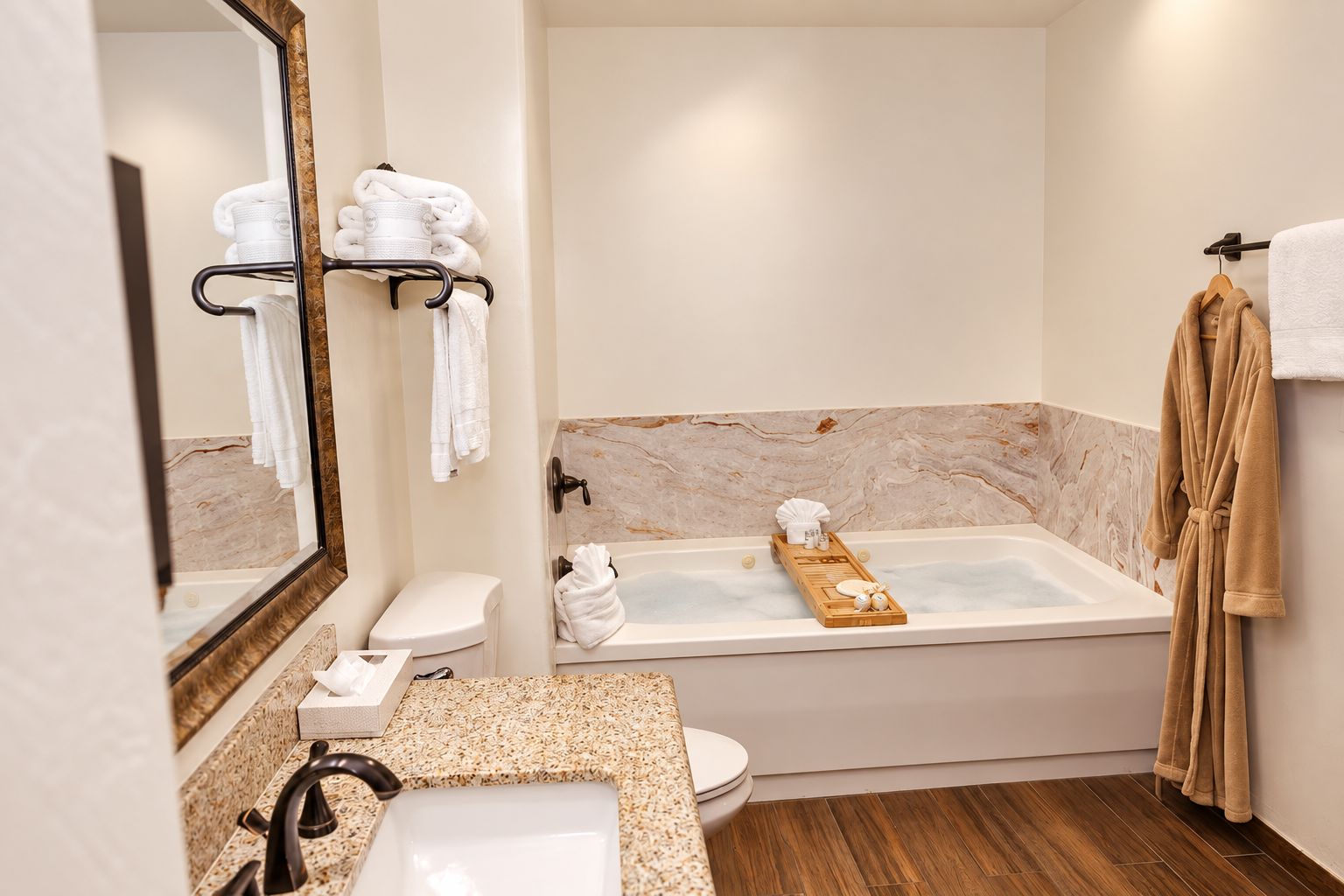 A modern bathroom with a marble vanity, a bathtub with a wooden tray, and a towel rack.