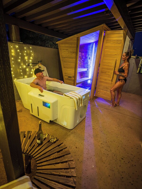 Una sauna con banca de madera, puerta de madera e iluminación colgante en la pared.