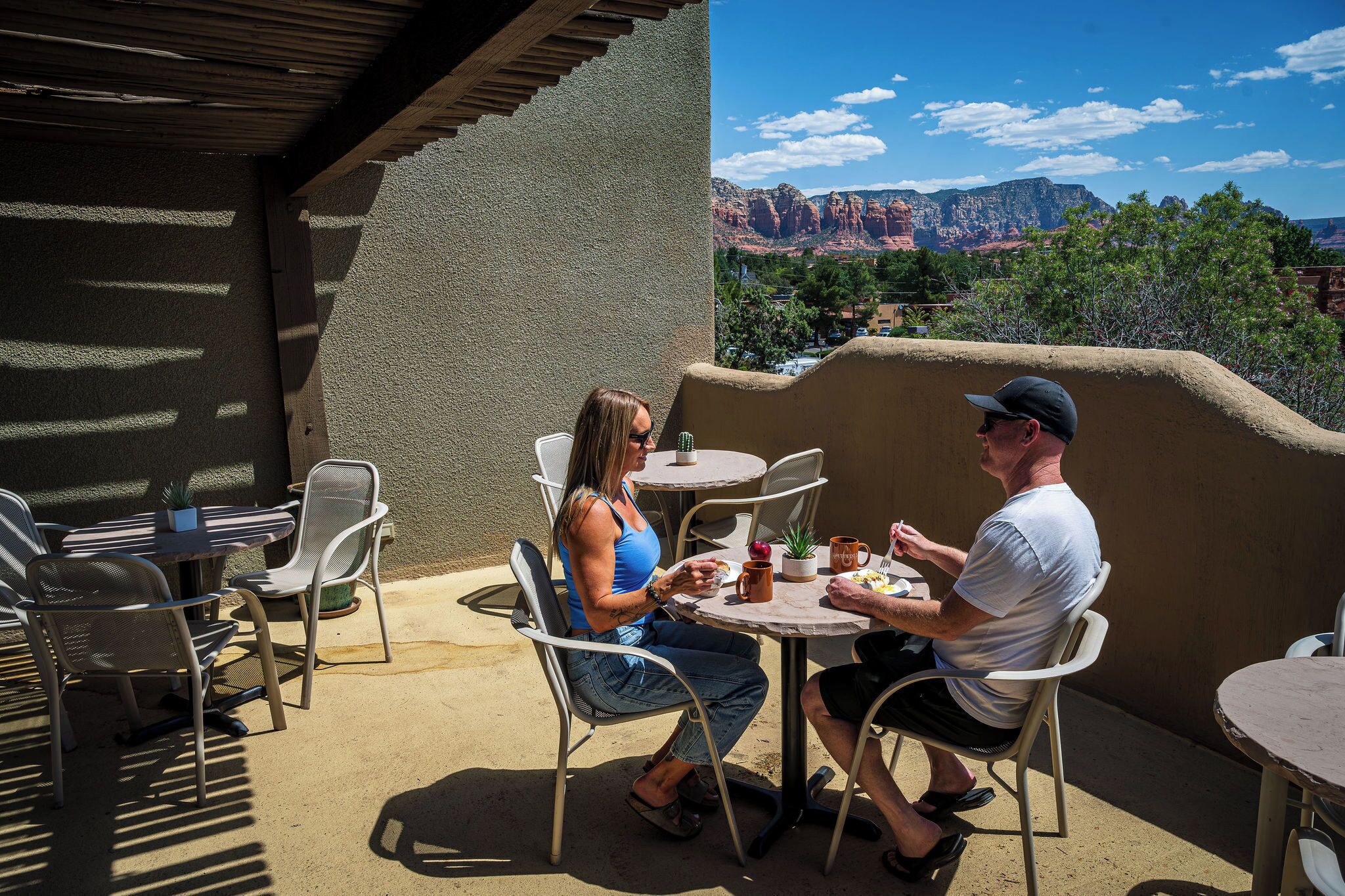 A patio with outdoor seating, a table with a plant, and a view of red rock formations.