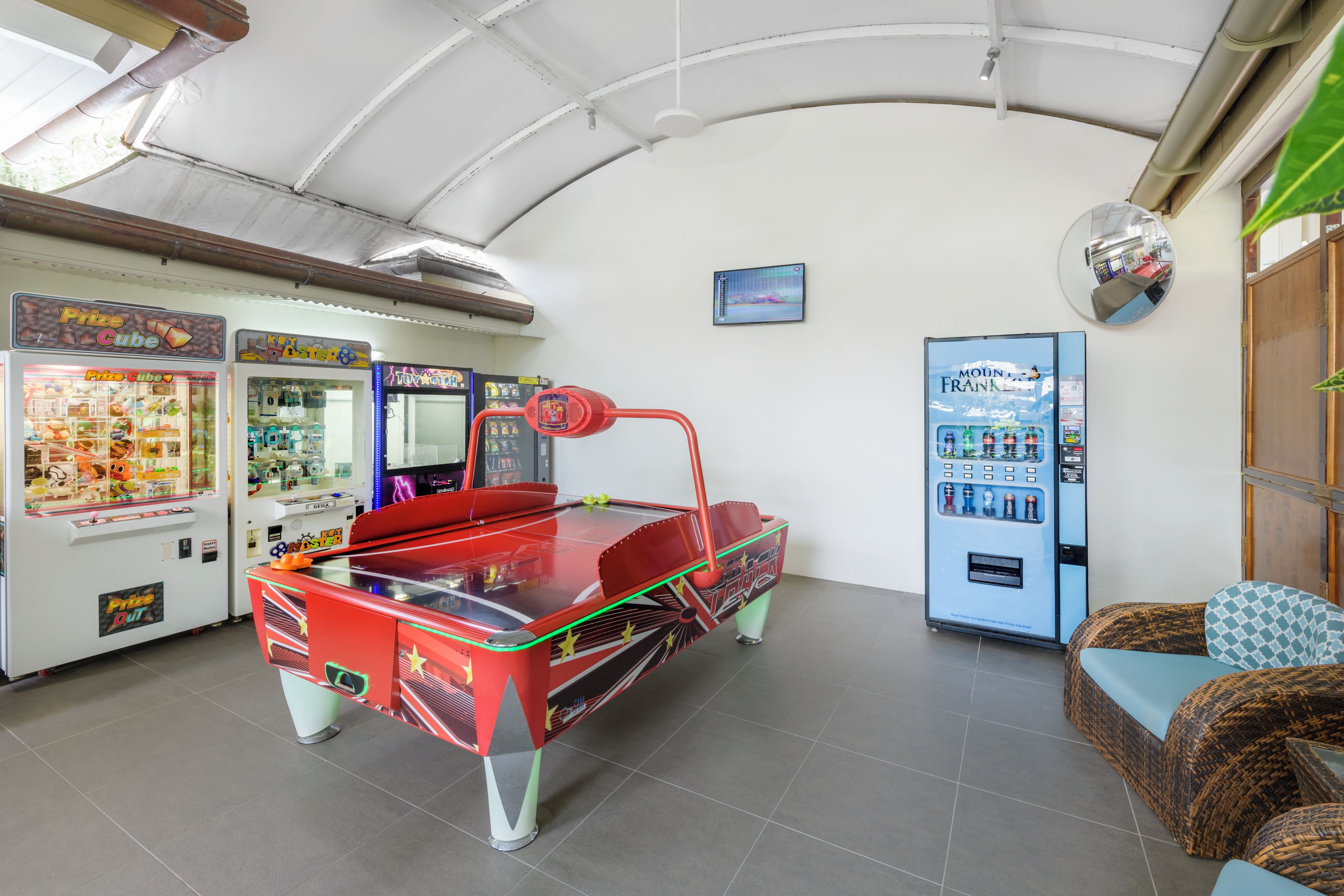Una habitación con máquinas de arcade, mesa de billar y un expendedor.
