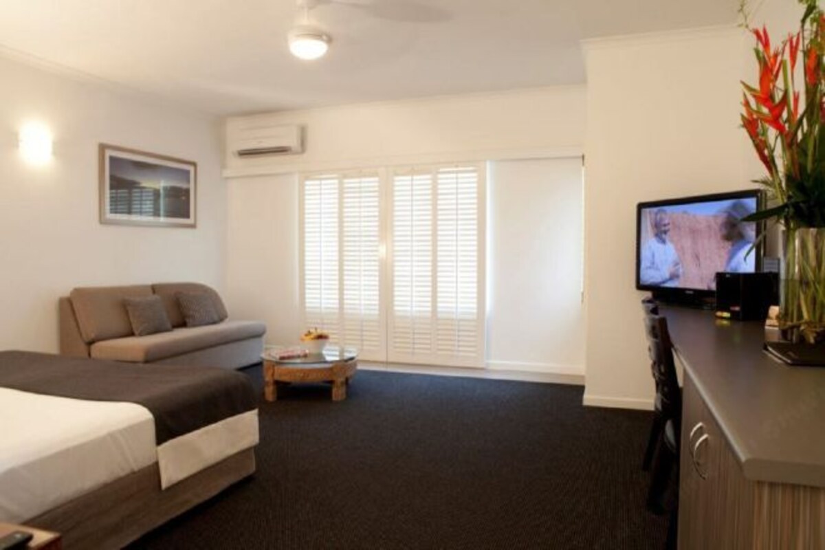 Une chambre d’hôtel avec un lit, un canapé, une télévision et une petite table.
