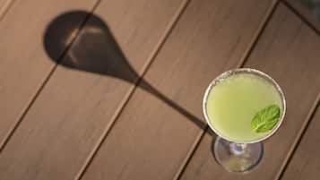 Un verre à cocktail orné d’une feuille de menthe, posé sur une table en bois.