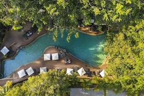 Una piscina al aire libre, sombrillas, sillones reclinables de piscina