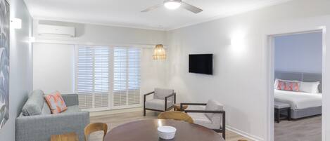 Una sala de estar moderna con una mesa redonda de madera, sofás grises y un ventilador de techo.