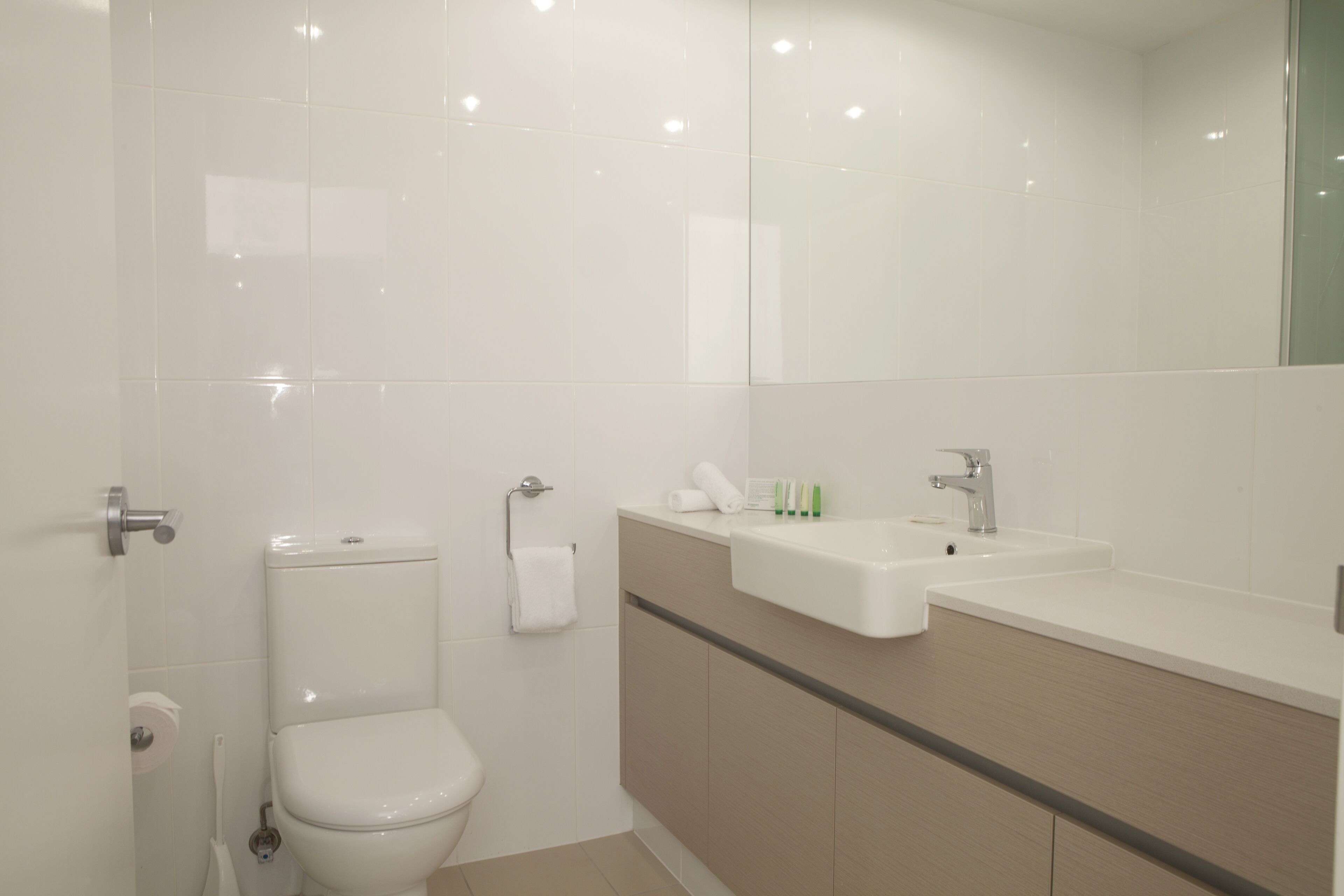 A modern bathroom with a toilet, sink, and mirror.