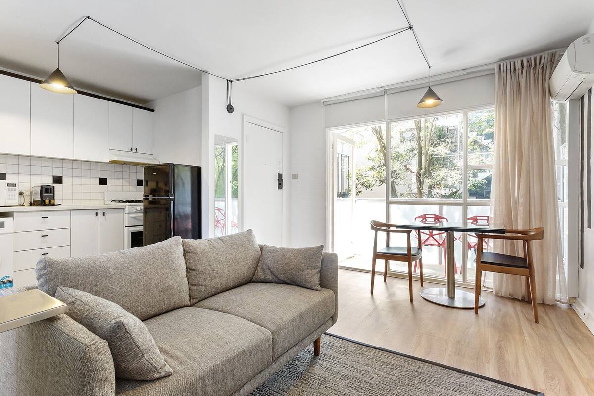 A modern kitchen with white cabinets, a refrigerator, and a dining area with a table and chairs.