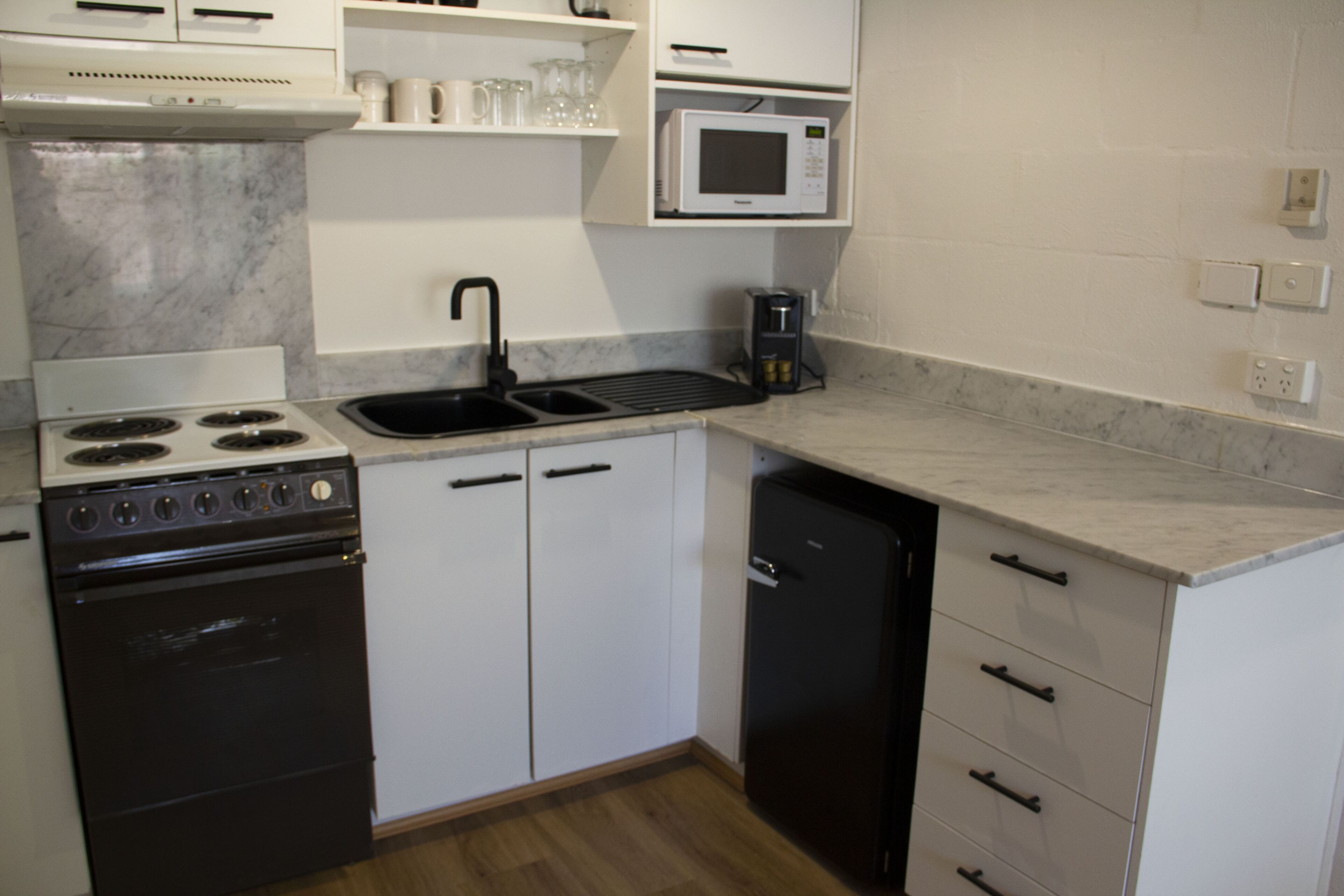 Una cocina compacta equipada con estufa, lavaplatos, microondas y cafetera.