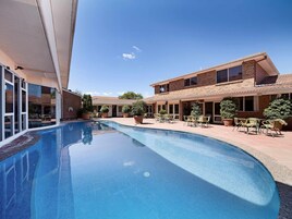 Una piscina al aire libre, sillones reclinables de piscina