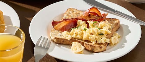 A breakfast plate with toast, scrambled eggs, and bacon.