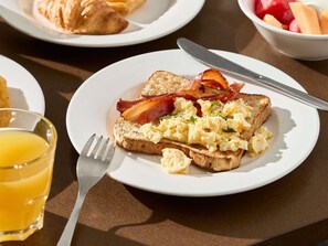 A breakfast plate with toast, scrambled eggs, and bacon.