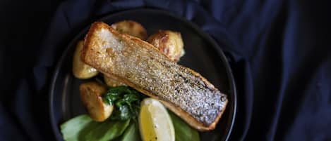 A plate with a piece of fish, potatoes, and greens.