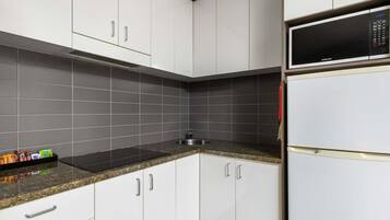 A kitchen with white cabinets, a black microwave, and a granite countertop.