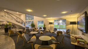 Un'ampia hall con una scalinata a forma di curva, diverse zone relax e ampie finestre che offrono vista sull'esterno.