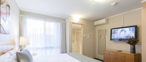 A hotel room with a bed, a TV, a dresser, and a bathroom door.