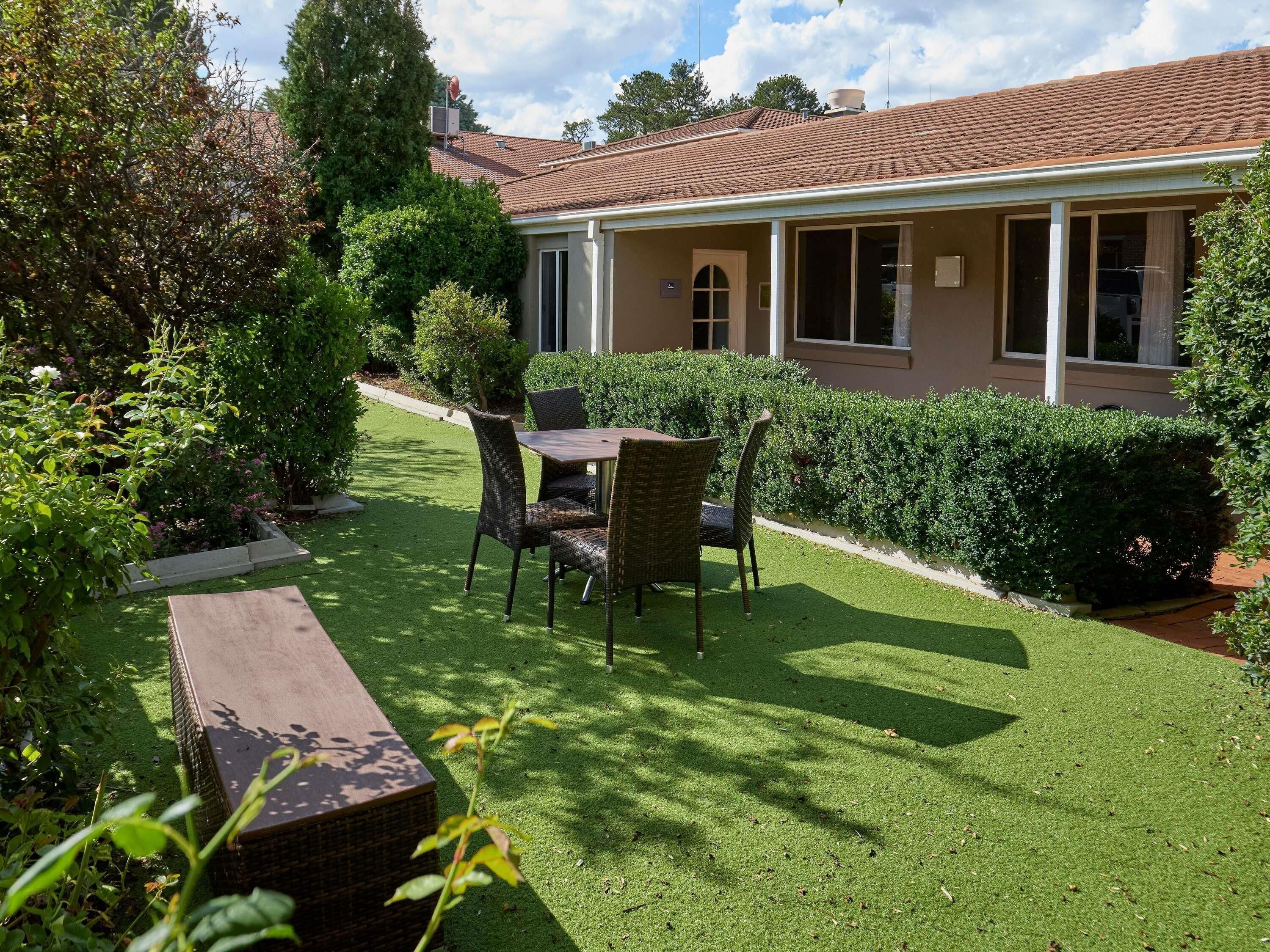 Una casa amb terrassa coberta, gespa i zona de jardí.