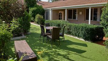 Una casa amb terrassa coberta, gespa i zona de jardí.
