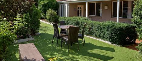 A house with a covered patio, a lawn, and a garden area.