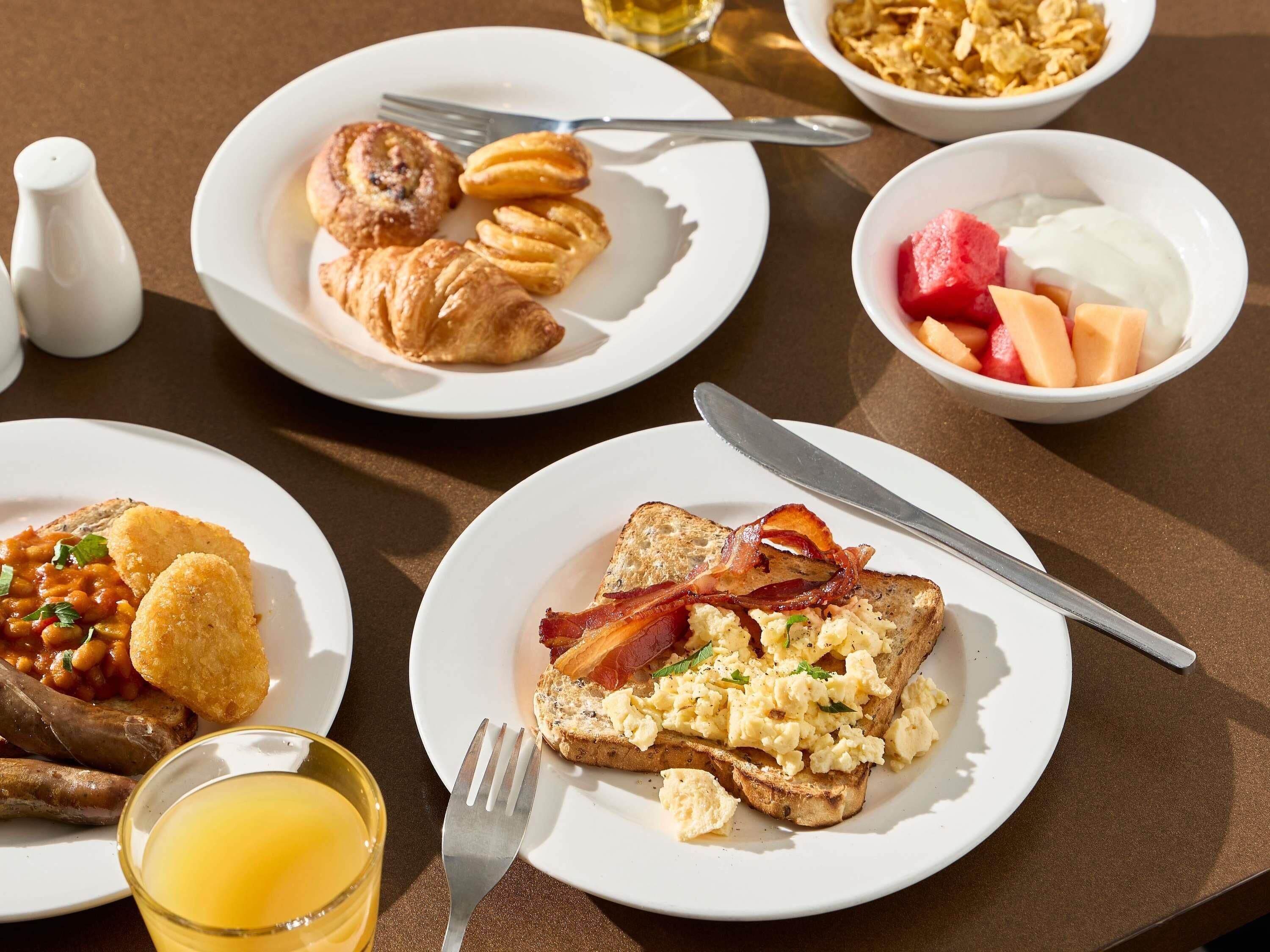 Ein Frühstückstisch mit Eiern, Toast, Croissants und Obst.