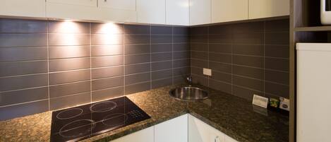 A kitchen with white cabinets, a stainless steel sink, and a built-in stove.