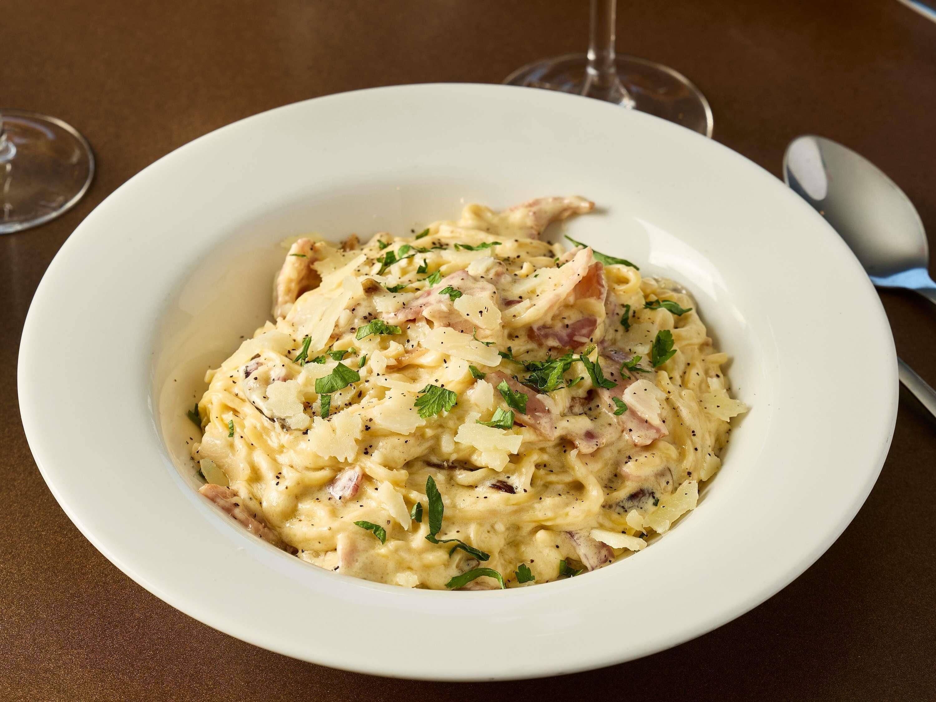 A bowl of creamy pasta with herbs on a table.